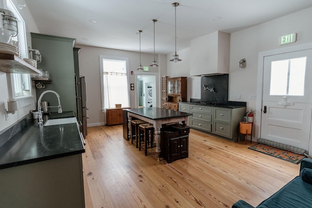 115 Rte 28, West Harwich, MA 02671 - kitchen featuring light wood finished floors, a kitchen breakfast bar, stacked washing maching and dryer, hanging light fixtures, and a sink