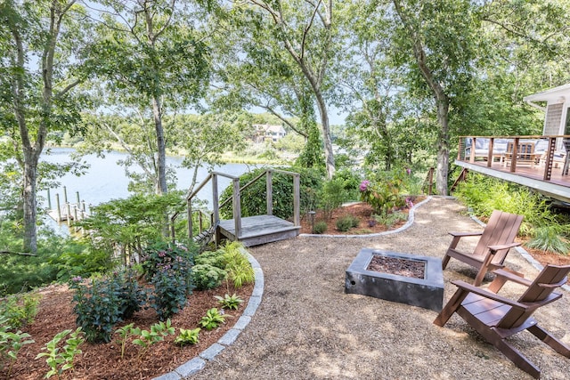 view of yard featuring an outdoor fire pit and a deck with water view