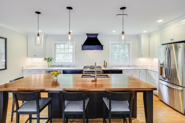 kitchen with stainless steel appliances, white cabinets, and custom exhaust hood