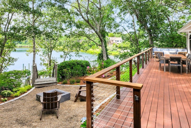 wooden terrace featuring a water view, an outdoor fire pit, and outdoor dining space