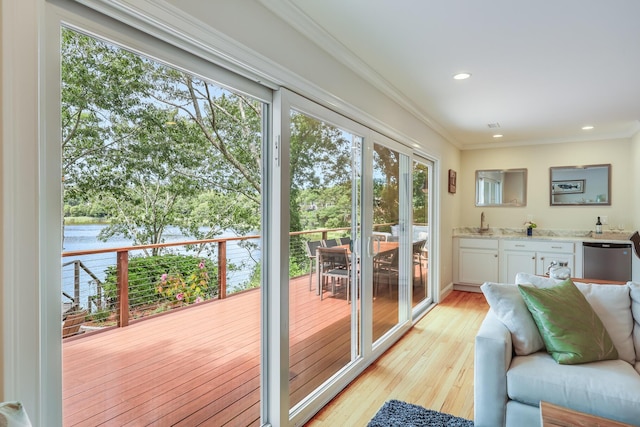 entryway with light wood-style flooring, ornamental molding, a water view, a sink, and recessed lighting