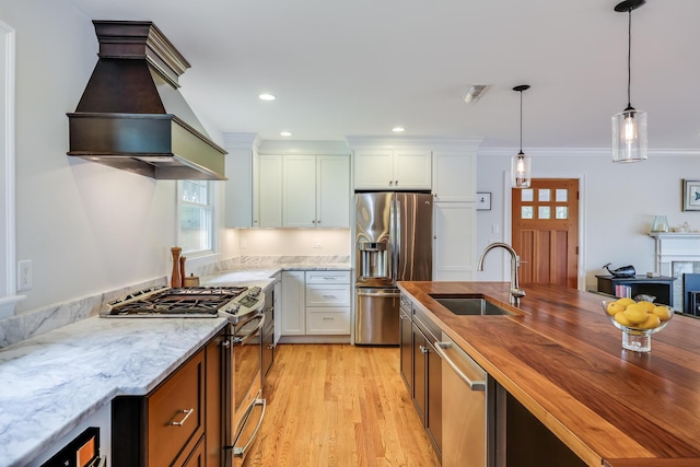 kitchen featuring pendant lighting, appliances with stainless steel finishes, a sink, and white cabinets