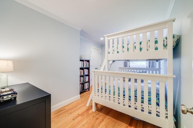 bedroom with light wood-style flooring, baseboards, and crown molding