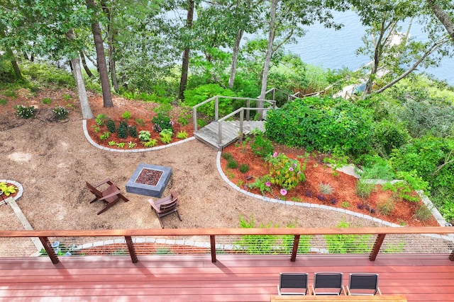 view of yard with a deck with water view and a fire pit