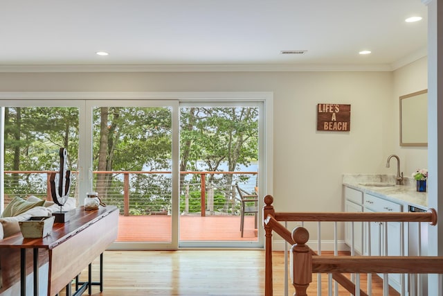 entryway with recessed lighting, visible vents, light wood-style flooring, ornamental molding, and a sink