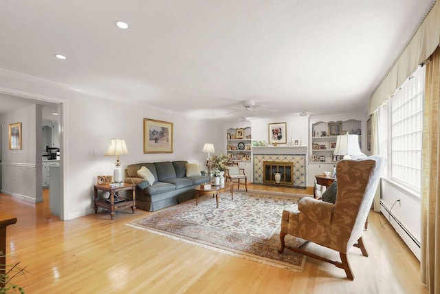 8 Viking Rock Rd, South Yarmouth, MA 02664 - living room with baseboard heating, a ceiling fan, light wood-style flooring, a tiled fireplace, and recessed lighting