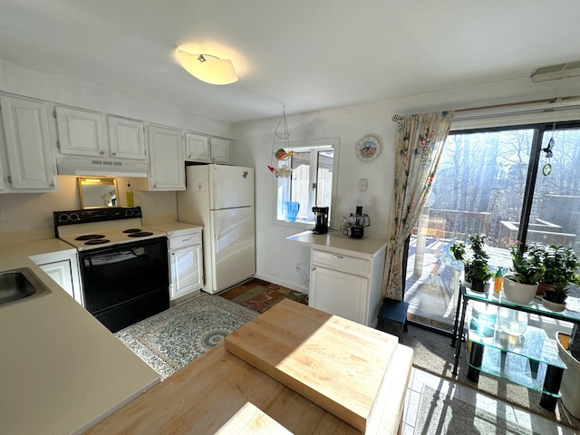 kitchen featuring sink, white fridge, white cabinets, and electric stove