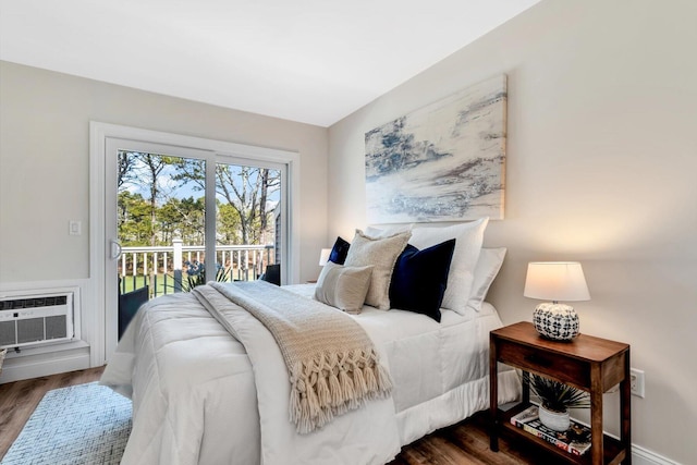 bedroom featuring access to exterior, dark wood-style floors, and an AC wall unit