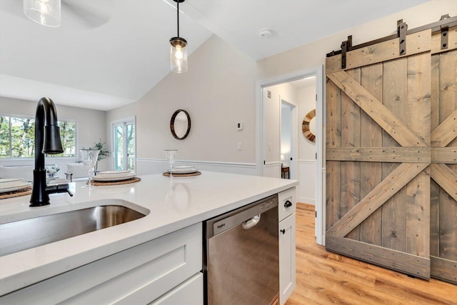 kitchen featuring dishwasher, a sink, light countertops, pendant lighting, and light wood finished floors