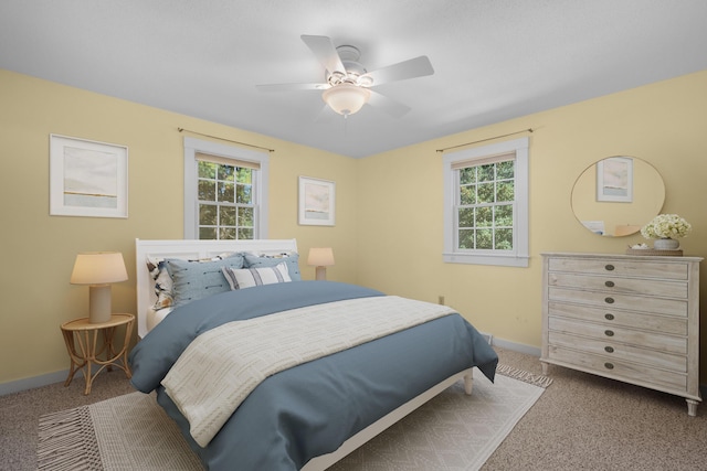 carpeted bedroom with multiple windows and ceiling fan