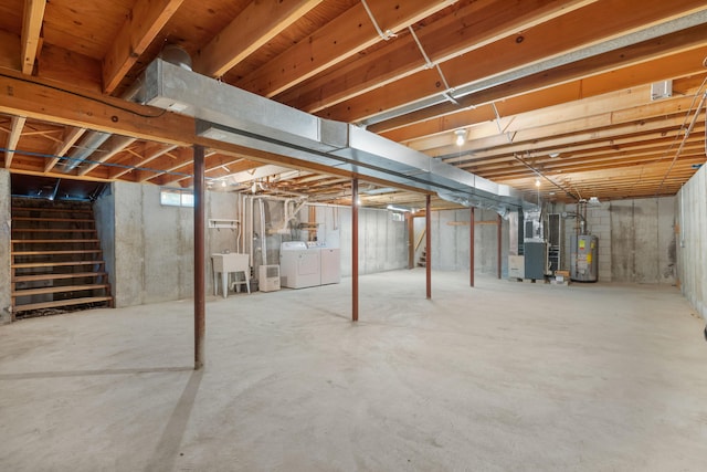 basement with sink, water heater, heating unit, and washer and clothes dryer