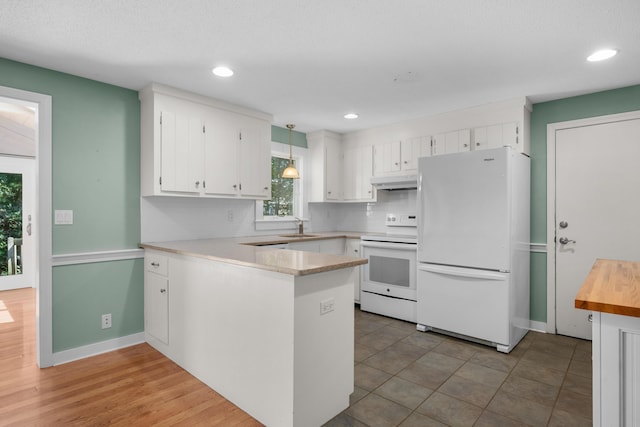 kitchen with white appliances, white cabinetry, sink, hanging light fixtures, and kitchen peninsula