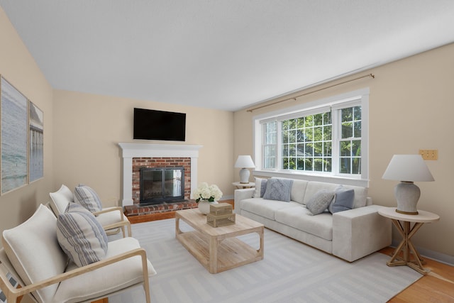 living room with a brick fireplace and wood-type flooring