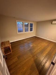 spare room featuring dark hardwood / wood-style flooring and a wall unit AC