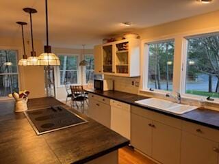 kitchen featuring pendant lighting, black electric stovetop, sink, light wood-type flooring, and white dishwasher