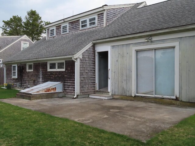 back of property with a patio and roof with shingles