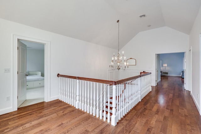 hallway featuring a notable chandelier, dark wood-type flooring, and lofted ceiling