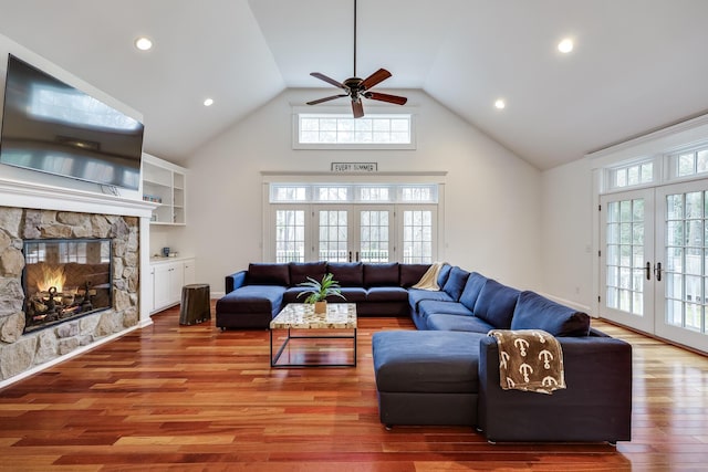 living room featuring french doors, hardwood / wood-style floors, a fireplace, and high vaulted ceiling