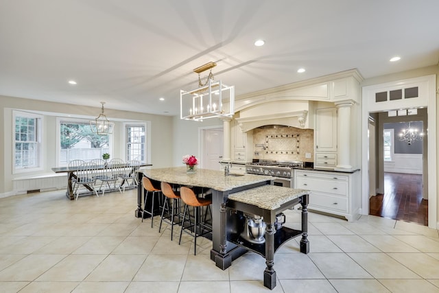 kitchen featuring pendant lighting, light stone counters, a breakfast bar, a chandelier, and high end stove