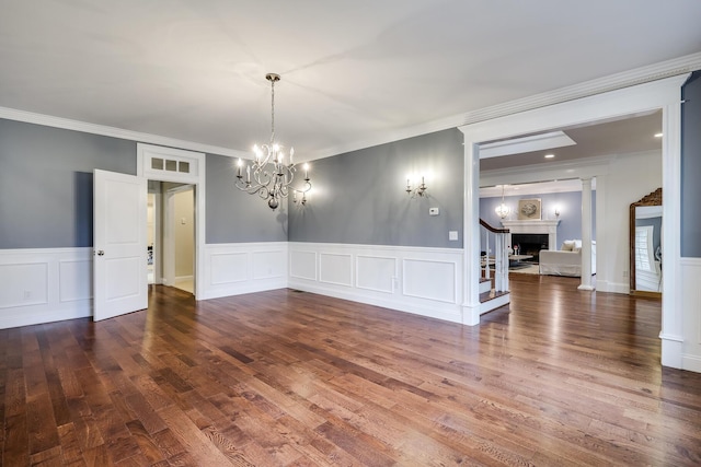 unfurnished room featuring dark hardwood / wood-style flooring, ornamental molding, and an inviting chandelier