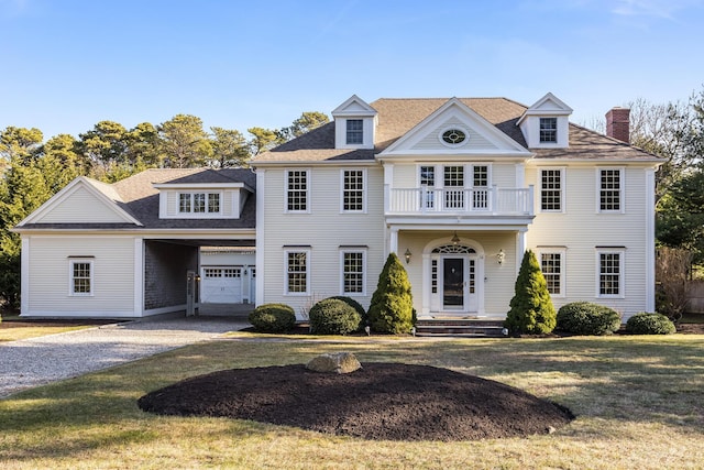 view of front facade featuring a balcony, a front lawn, and a garage