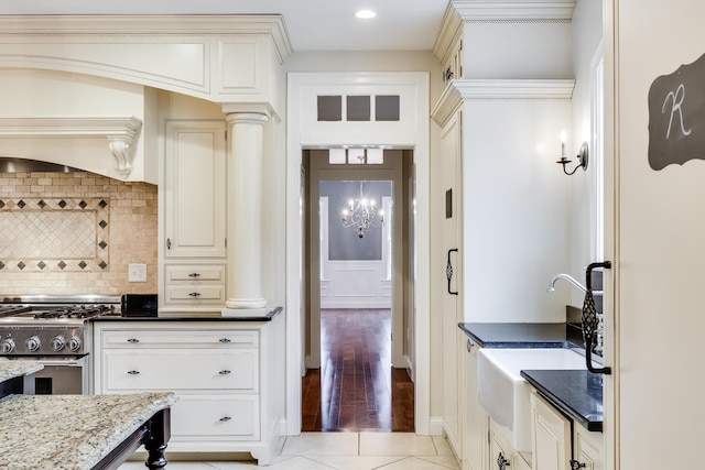 kitchen with sink, tasteful backsplash, light tile patterned floors, dark stone counters, and high end range