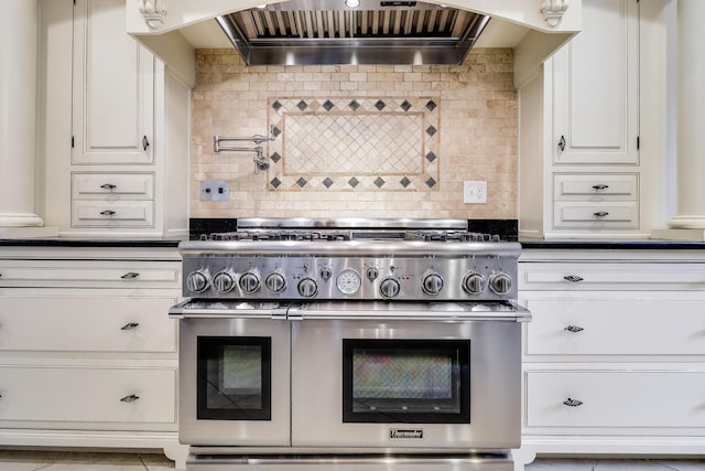 kitchen featuring backsplash, range with two ovens, white cabinets, and custom exhaust hood