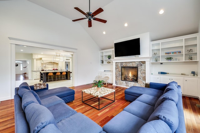 living room featuring a fireplace, wood-type flooring, ceiling fan, and vaulted ceiling