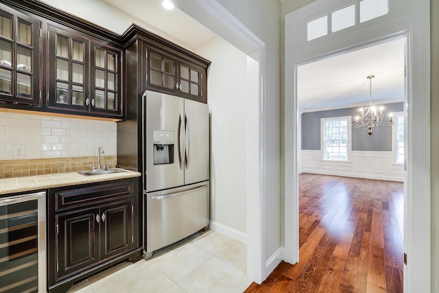 kitchen with sink, stainless steel fridge, dark brown cabinetry, and wine cooler