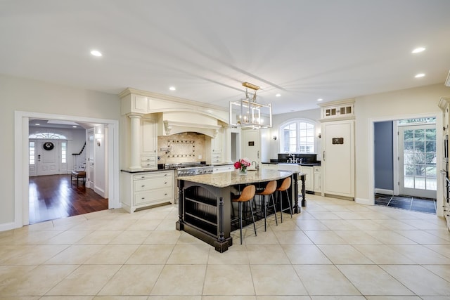 kitchen with a center island, high end range, light stone countertops, light tile patterned floors, and pendant lighting