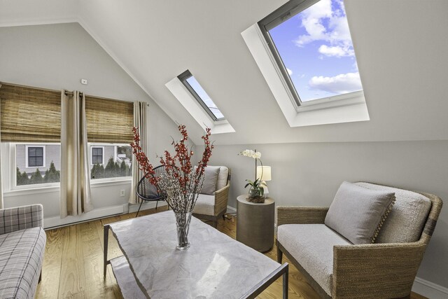 living area with vaulted ceiling with skylight and wood-type flooring