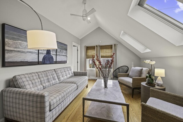 living room with light wood-type flooring, ceiling fan, and lofted ceiling with skylight