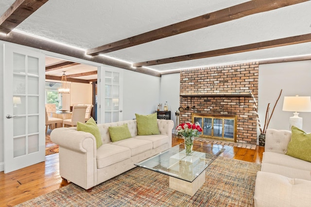 28 Brook St, Plympton, MA 02367 - living room featuring hardwood / wood-style flooring, beamed ceiling, a chandelier, a brick fireplace, and french doors