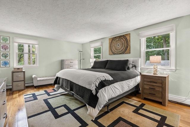 28 Brook St, Plympton, MA 02367 - bedroom with wood finished floors, baseboard heating, a textured ceiling, and a baseboard heating unit