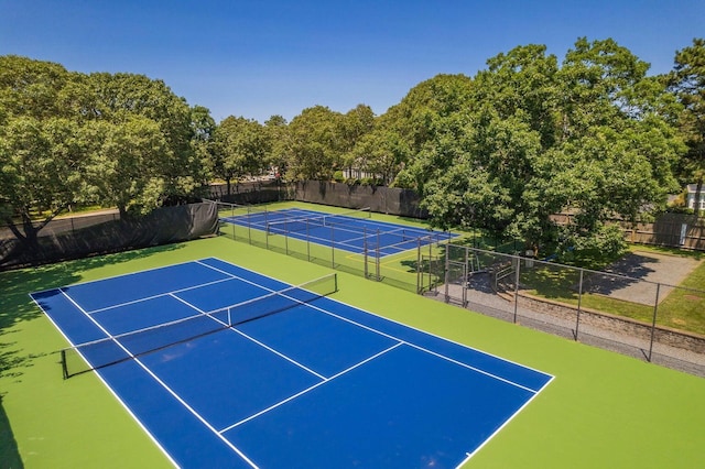 view of tennis court with basketball hoop and fence