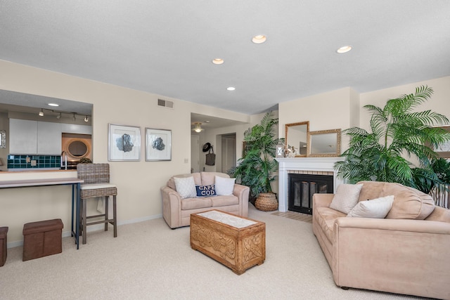 living area featuring visible vents, baseboards, a fireplace with flush hearth, recessed lighting, and light carpet