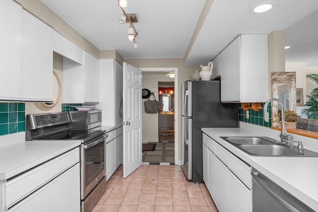 kitchen with a sink, appliances with stainless steel finishes, white cabinets, and light countertops