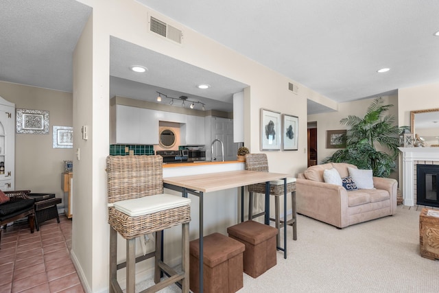 kitchen featuring tasteful backsplash, visible vents, wooden counters, and a breakfast bar area