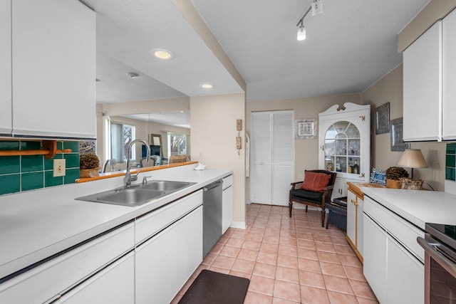 kitchen featuring tasteful backsplash, light countertops, appliances with stainless steel finishes, white cabinetry, and a sink