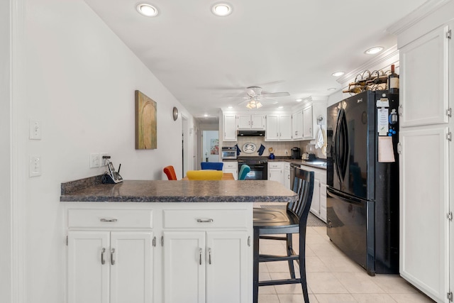 64 Gold Finch Ln, South Dennis, MA 02660 - kitchen with a peninsula, light tile patterned floors, dark countertops, white cabinetry, and black appliances