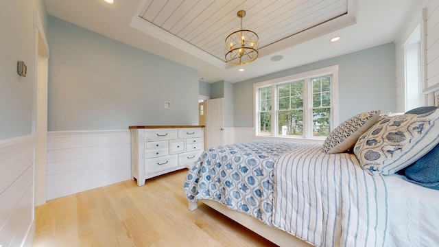 bedroom featuring a chandelier, light hardwood / wood-style flooring, and a tray ceiling