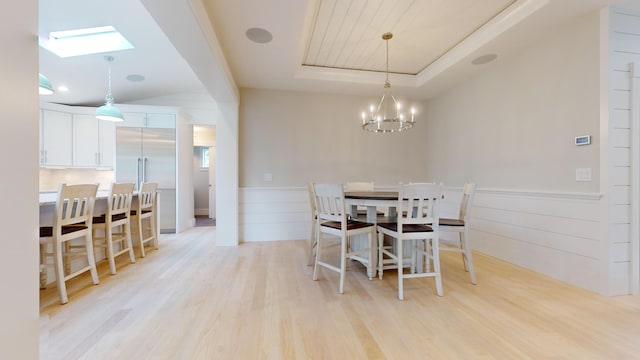 dining area featuring light hardwood / wood-style flooring, a notable chandelier, and a raised ceiling