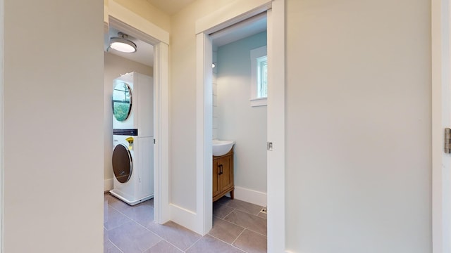 washroom featuring stacked washer / drying machine and light tile patterned flooring