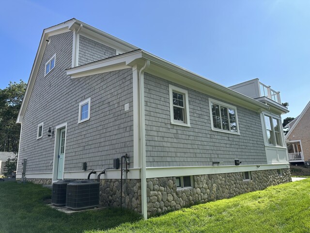 view of side of property featuring central AC unit and a lawn