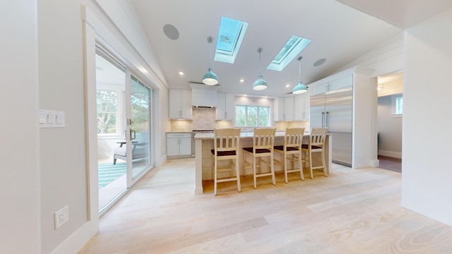 kitchen with white cabinetry, hanging light fixtures, a center island, and a breakfast bar area