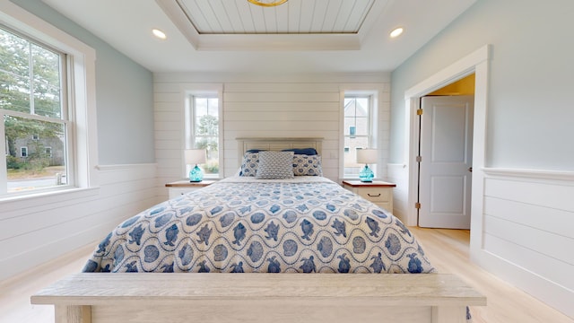 bedroom featuring light hardwood / wood-style floors and a tray ceiling