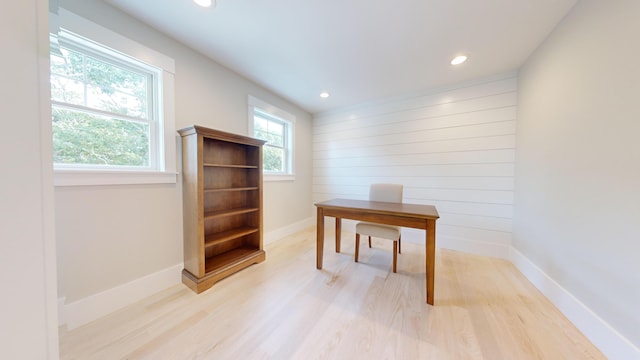 office with wood walls and light hardwood / wood-style flooring