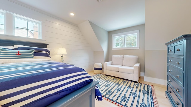 bedroom with light hardwood / wood-style floors and wooden walls