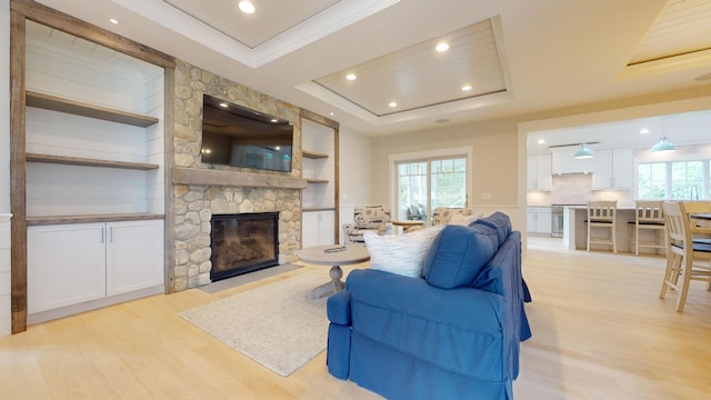 living room featuring a fireplace, built in features, light wood-type flooring, and a healthy amount of sunlight