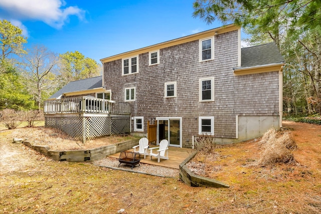 rear view of house featuring a wooden deck and roof with shingles